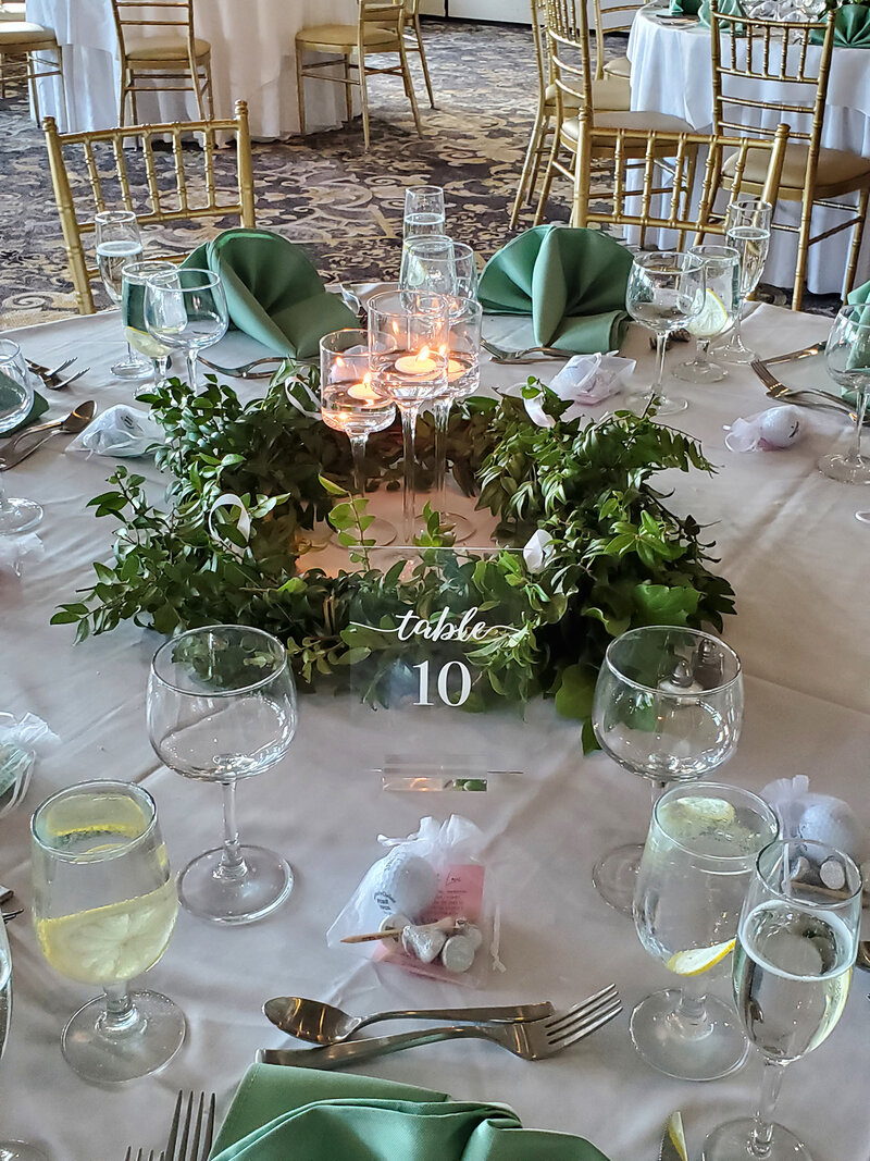 Table with green napkins, glasses and a flower arrangement