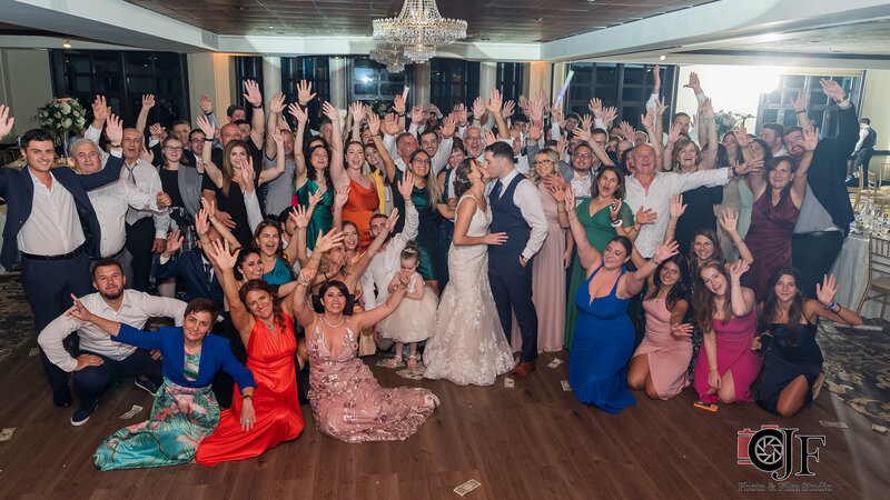 Bride and groom kissing with wedding guest cheering