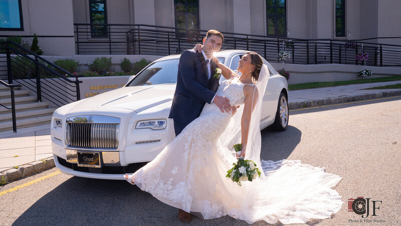 Groom embracing bride in front of car