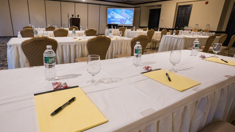 Long table with note pads, bottled water and glasses